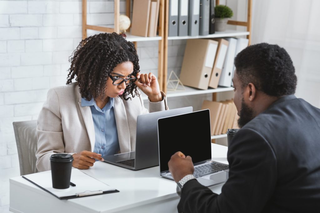 Millennial African American businesswoman having conflict with collague at workplace, empty space